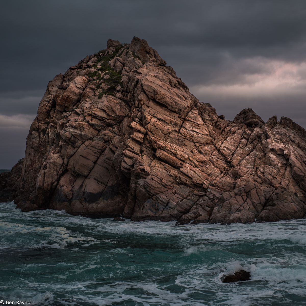 Sugar Loaf Rock, rock appearing out of rough seas, with soft morning light